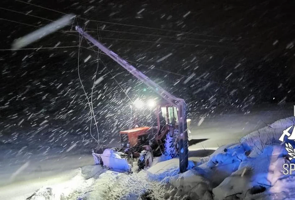 Podczas odśnieżania drogi ciągnik spadł ze skarpy i zniszczył słup. Traktorzysta uwięziony w kabinie (FOTO)